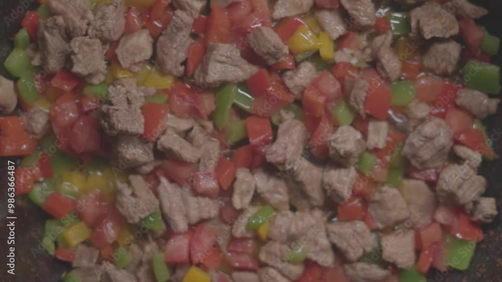 Closeup top view of meat pieces with vegetables getting cooked in the frying pot on the stove