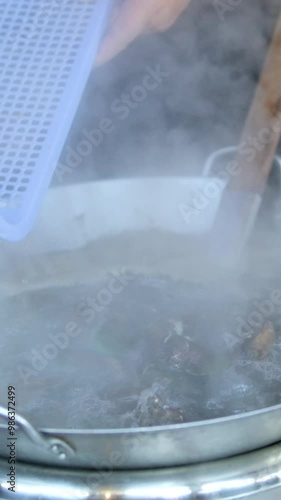 throw shells into hot water pour the clams into the boiling water from the blue plastic container into the pan photo