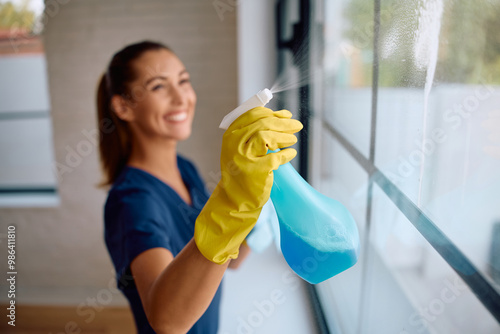 Close up of cleaner spraying windows with detergent mix.