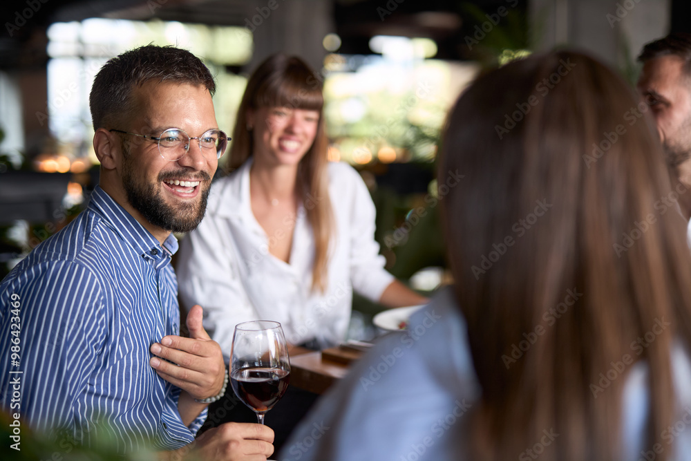 Happy entrepreneur talking to his colleagues during lunch break in restaurant. Happy entrepreneur talking to his colleagues during lunch break in restaurant.
