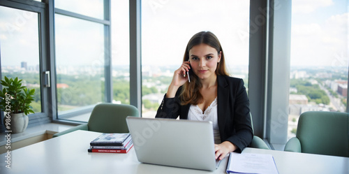 A confident businesswoman is discussing a new strategy over the phone in a bright and productive office. 