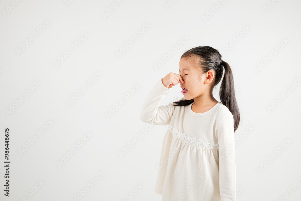 Asian young child unhappy what smell disgust expression squeezing nose with fingers. Kid girl kindergarten have something stinks bad smell situation, studio shot isolated on white background Asian young child unhappy what smell disgust expression squeezing nose with fingers. Kid girl kindergarten have something stinks bad smell situation, studio shot isolated on white background