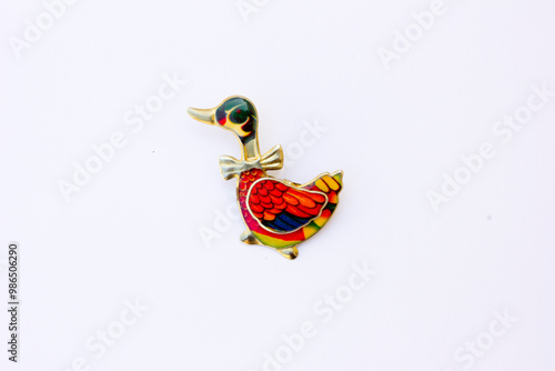 A colorful brooch shaped like a duck. A brooch is a piece of jewelry that serves both functional and decorative purposes. This photo is taken from the front. photo