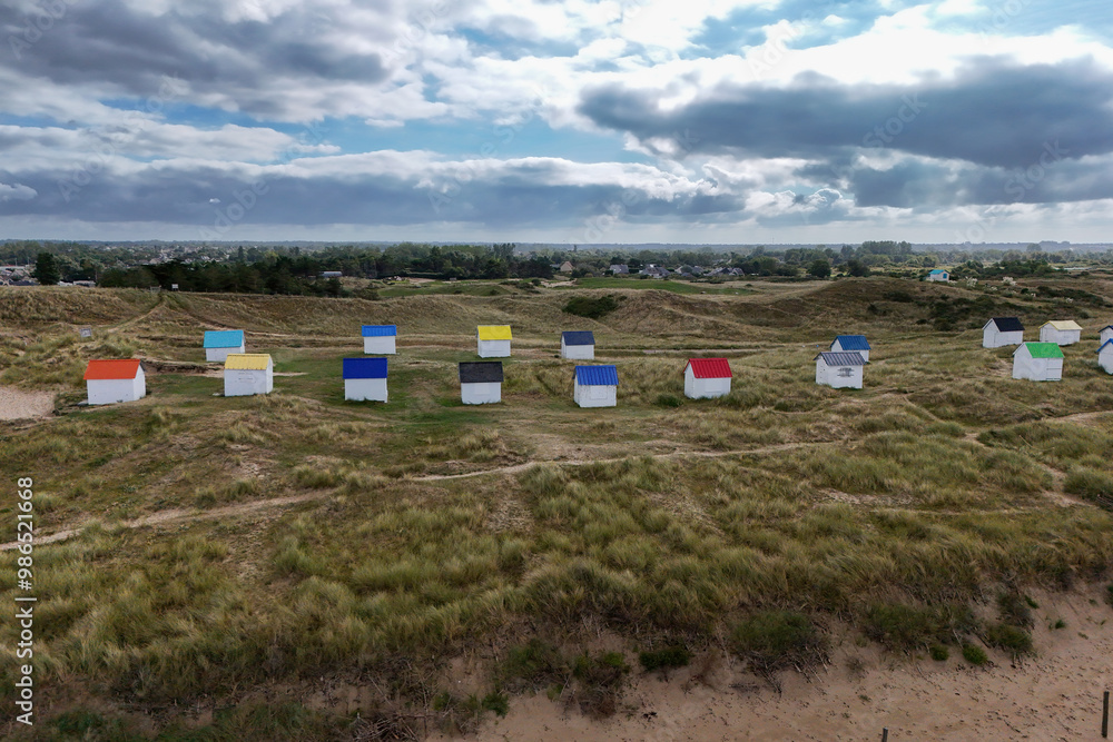 White beach huts with coloured roofs on the beach at Gouville-sur-mer in Normandy, France White beach huts with coloured roofs on the beach at Gouville-sur-mer in Normandy, France