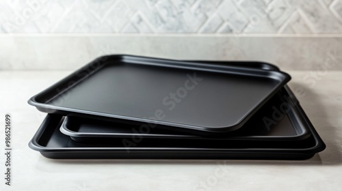 Non-stick cookie sheets stacked neatly, isolated on a light ceramic countertop