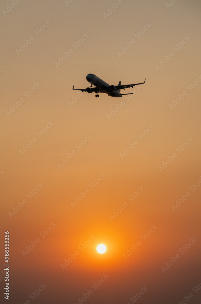 Passenger plane is landing on the background of the setting sun Passenger plane is landing on the background of the setting sun