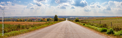 Old Wisconsin road going through farmland and colorful trees at the end of summer