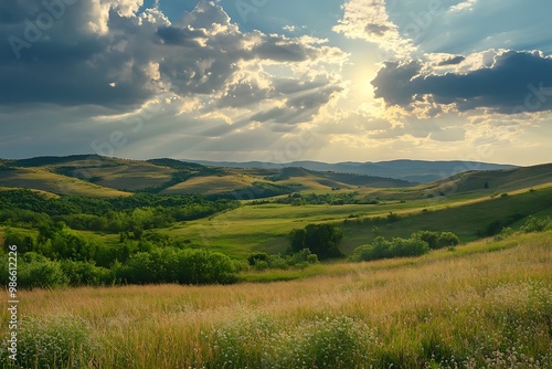 Sun shining through clouds above green hills and meadow landscape