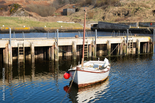 A small white boat moored in Lybster harbour Scotland photo