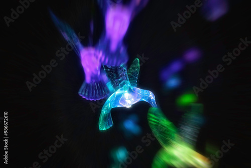 Glass hummingbird ornaments with colourful lighting at night, nobody