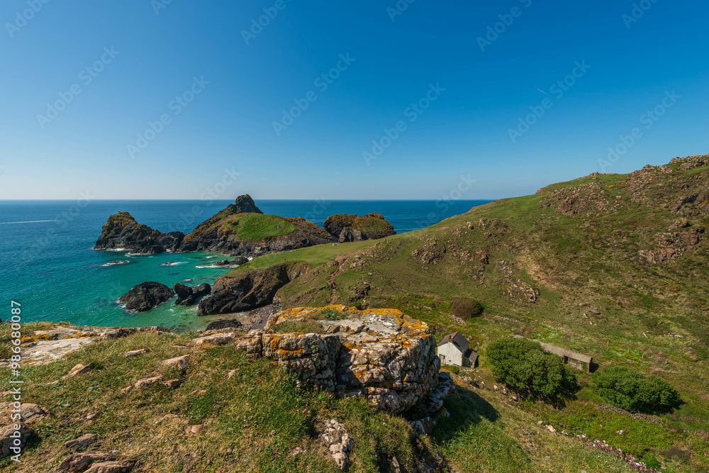 Panoramic view of Kynance Cove's dramatic coastline and turquoise waters on a sunny day in Cornwall, England. Panoramic view of Kynance Cove's dramatic coastline and turquoise waters on a sunny day in Cornwall, England.
