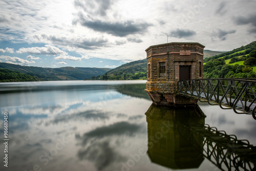 Talybont Reservoir: Stone valve tower reflected in calm water under cloudy Welsh sky. photo