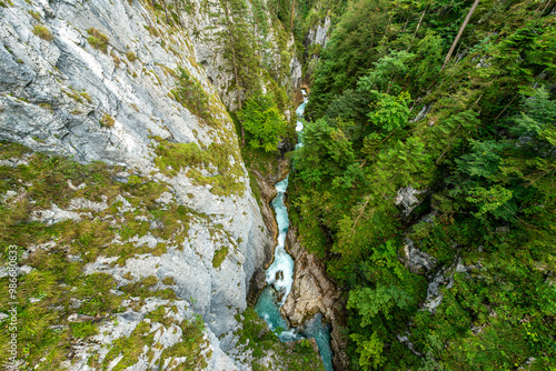 Tableau sur toile Aerial view of narrow gorge with turquoise river flowing through lush green forest in Alps