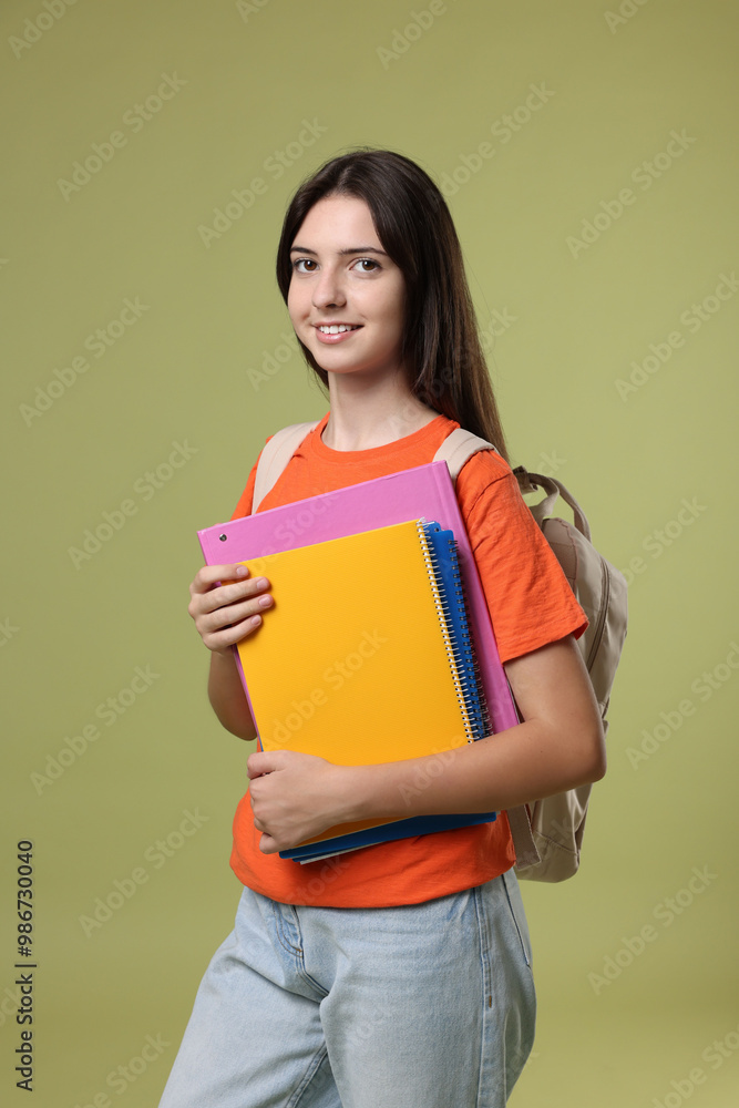 Portrait of cute teenage girl with backpack and books on olive background Portrait of cute teenage girl with backpack and books on olive background