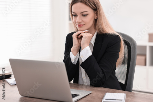 Banker with laptop working at wooden table in office