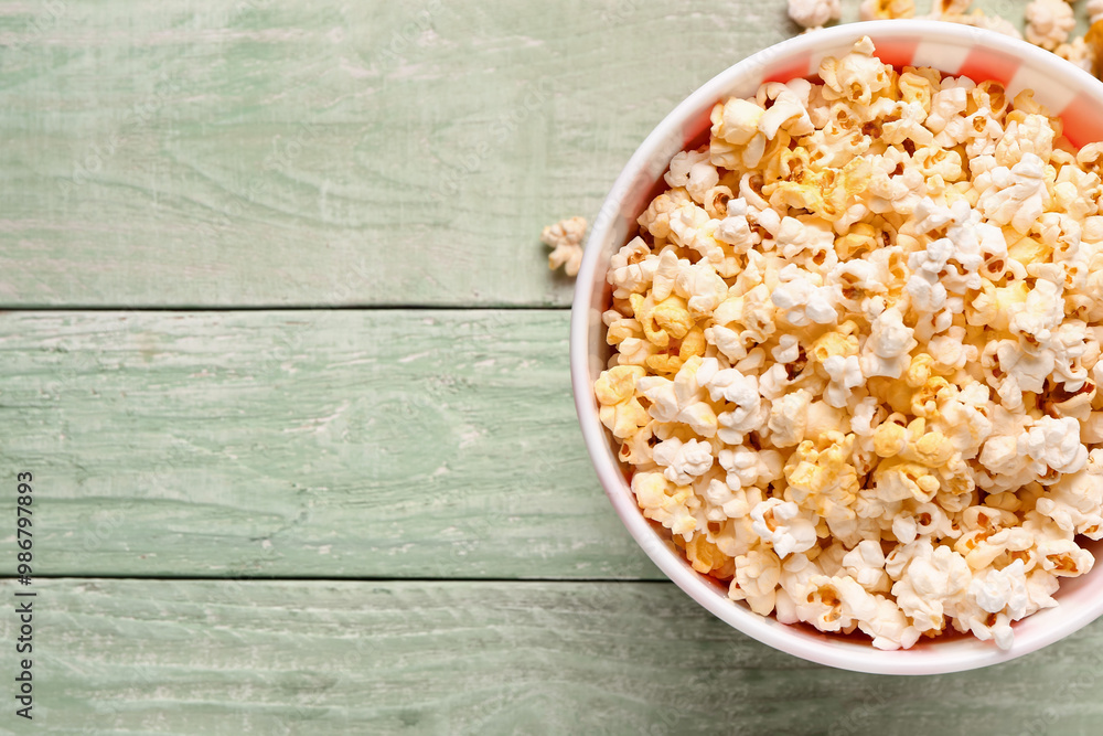 Bucket with tasty popcorn on green wooden background Bucket with tasty popcorn on green wooden background