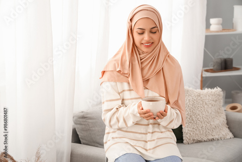 Young Muslim woman with cup...