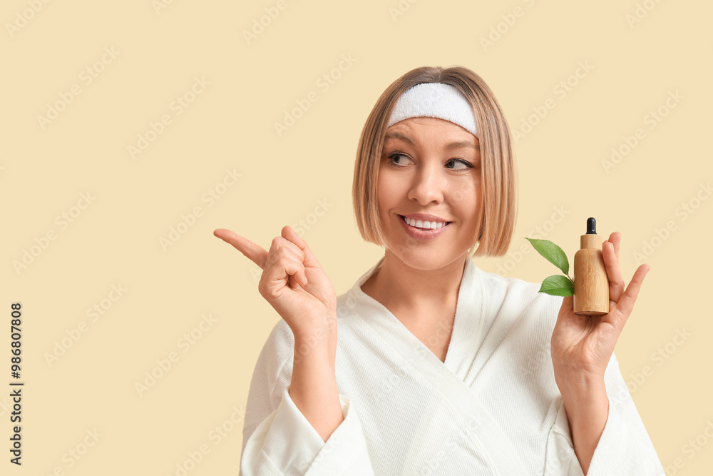 Beautiful mature woman with bottle of essential oil pointing at something against color background Beautiful mature woman with bottle of essential oil pointing at something against color background