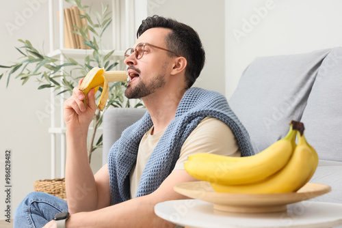 Young man eating banana at ...