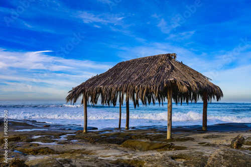  2023-12-31 A GRASS HUT ON A ROCKY SHORLINE WITH WAVES COMING SHORE AT THE WINDANSEA BEACH IN LA JOLLA CALIFORNIA NEAR SAN DIEGO  photo