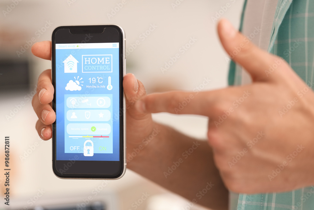 Young man pointing at mobile phone with smart home application in kitchen, closeup Young man pointing at mobile phone with smart home application in kitchen, closeup