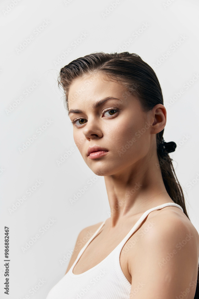 Portrait of a young woman with a neutral expression against a light gray background, showcasing natural beauty and simplicity Capturing elegance and confidence in a minimalistic setting Portrait of a young woman with a neutral expression against a light gray background, showcasing natural beauty and simplicity Capturing elegance and confidence in a minimalistic setting