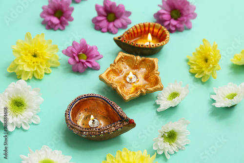 Diya lamps with flowers on turquoise background. Divaly celebration photo