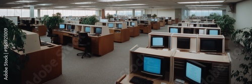 Wide shot of a vintage office featuring rows of cubicles with desktops, highlighting an old-fashioned work style.