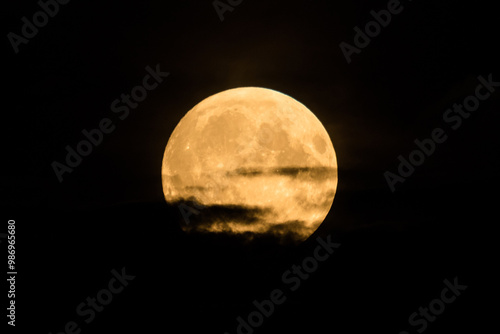 Beautiful bright and vivid landscape or background of large fool shiny romantic or horror Moon with craters in cloudy night sky 