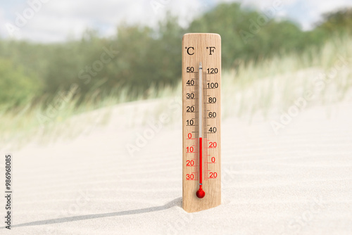 Wooden celsius and fahrenheit scale thermometer in the sand. Ambient temperature plus 1 degrees