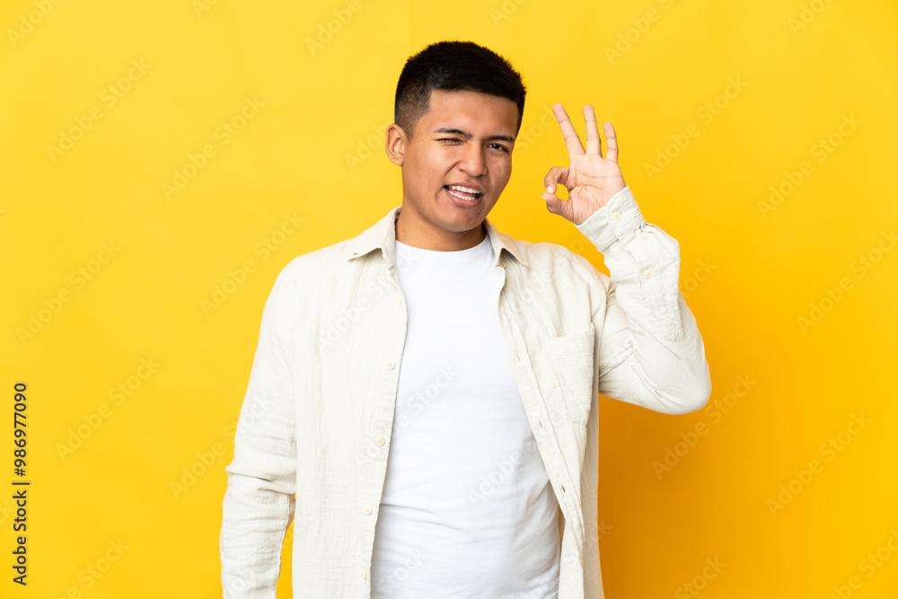 Young Ecuadorian man isolated on yellow background showing ok sign with fingers Young Ecuadorian man isolated on yellow background showing ok sign with fingers
