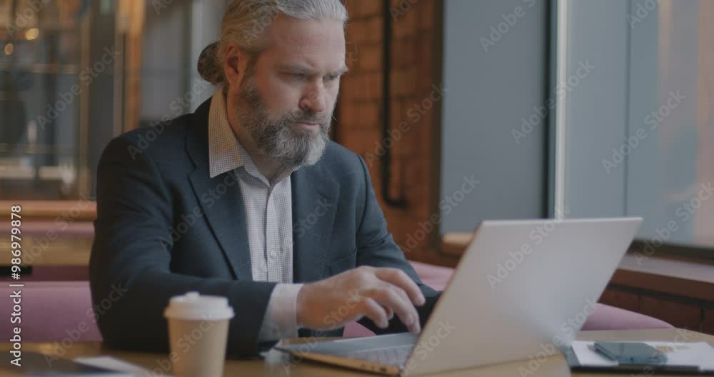 Slow motion portrait of mature businessman working with laptop then looking at camera and smiling at table in cafe. Business and technology concept. Slow motion portrait of mature businessman working with laptop then looking at camera and smiling at table in cafe. Business and technology concept.