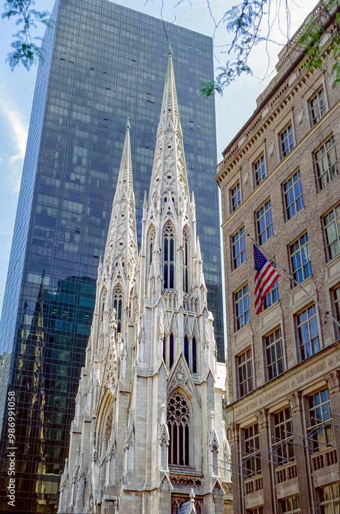 Obraz premium Eingescanntes Diapositiv einer historischen Farbaufnahme der Frontfassade mit den zwei Türmen des St. Patrick's Cathedral in Manhattan, New York, USA inmitten von Bürohochhäusern