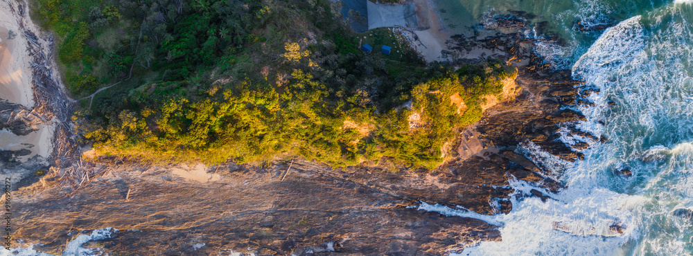 Aerial panorama view of a coastal headland surrounded by waves crashing on to rocky ledges Aerial panorama view of a coastal headland surrounded by waves crashing on to rocky ledges