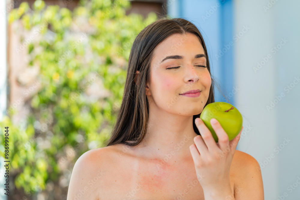 Young pretty Brazilian woman at outdoors holding an apple Young pretty Brazilian woman at outdoors holding an apple