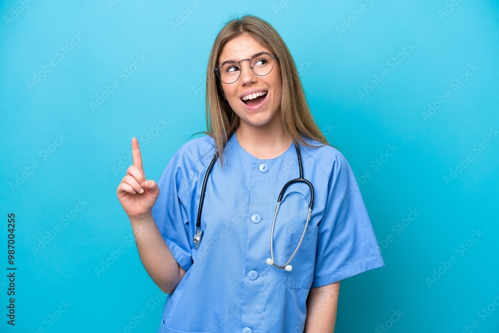 Young surgeon doctor woman isolated on blue background pointing up and surprised Young surgeon doctor woman isolated on blue background pointing up and surprised
