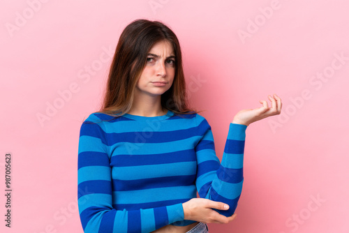 Young caucasian woman isolated on pink background having doubts