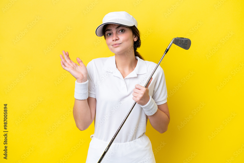young caucasian woman playing golf isolated on yellow background having doubts while raising hands young caucasian woman playing golf isolated on yellow background having doubts while raising hands