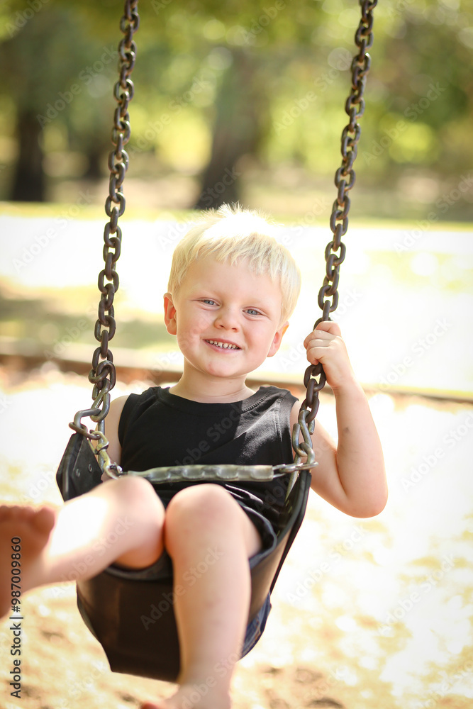 Child playing on swing at playground in Summer Child playing on swing at playground in Summer