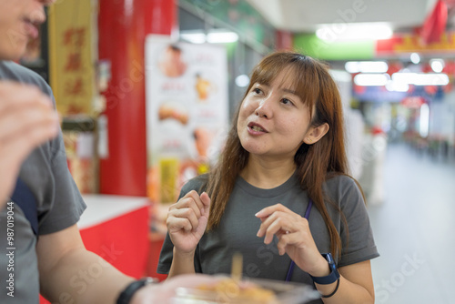 Chinese Malaysian couple in their 30s buying and eating kinako mochi dessert at shop in Chinese temple in Kuala Lumpur, Malaysia. photo