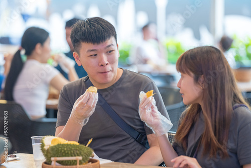 Chinese Malaysian couple in their 30s chatting while eating durian at a famous shop popular with tourists in Kuala Lumpur, Malaysia. photo