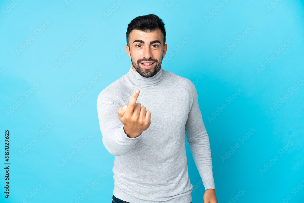 Caucasian man over isolated blue background doing coming gesture Caucasian man over isolated blue background doing coming gesture