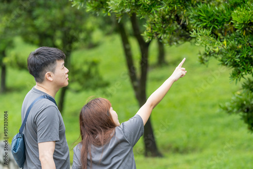 Photography Chinese Malaysian couple in their 30s walking closely together in a lush, water-filled park in Kuala Lumpur, Malaysia