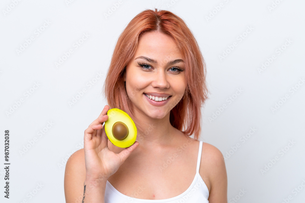 Young Russian girl isolated on white background holding an avocado while smiling. Close up portrait Young Russian girl isolated on white background holding an avocado while smiling. Close up portrait