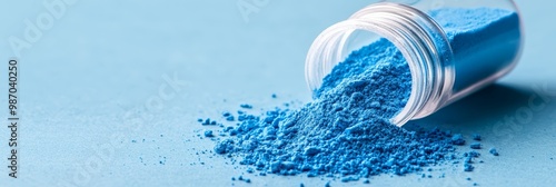  A glass jar, brimming with blue powder, sits atop a blue table Nearby, a mound of identical blue powder amasses photo