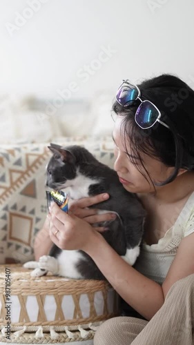 Chinese and Indian Malaysian couple in their 20s and 31s playing with a cat in a room with Western-style furniture in a house in Selangor, Malaysia. photo