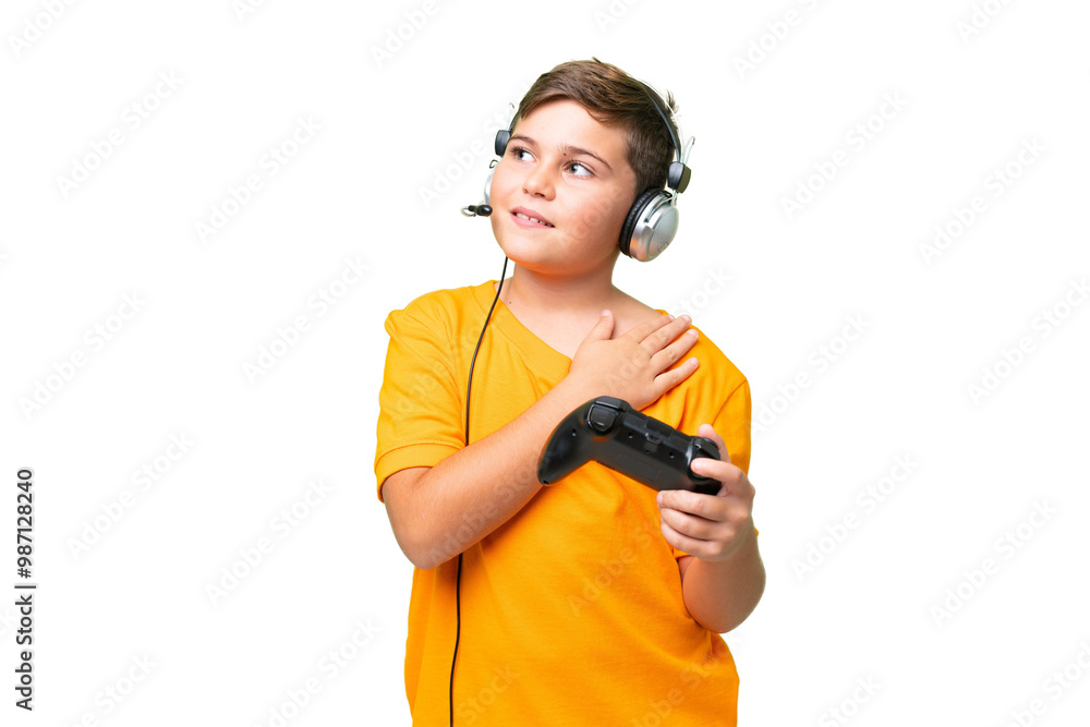 Little caucasian kid playing with a video game controller over isolated chroma key background looking up while smiling Little caucasian kid playing with a video game controller over isolated chroma key background looking up while smiling
