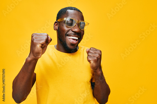 Papier peint Happy man celebrating joyfully in a bright yellow shirt and sunglasses against a