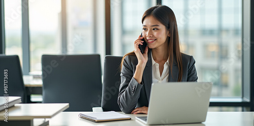 A  business woman is discussing a new strategy over the phone in a bright and productive office (with copy space).