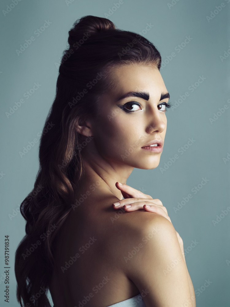 Naklejka premium Makeup, serious and portrait of woman in studio with facial cosmetics routine for glow. Confident, eyeliner and young female person with face for beauty cosmetology isolated by blue background.